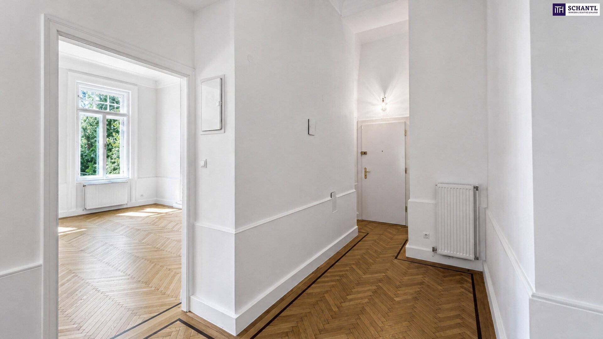Eleganter Flur mit Fischgrätparkett, der zu einem hellen Zimmer führt und den klassischen Stil des Gebäudes unterstreicht.
