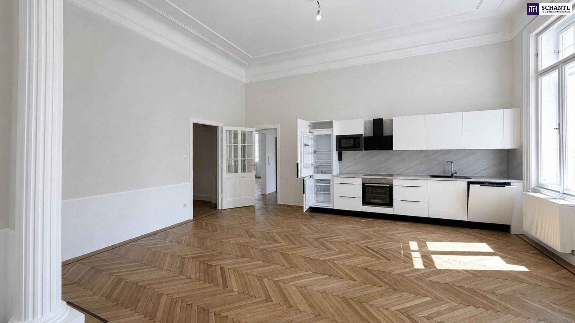 Großer Raum mit Fischgrätparkett und einer modernen, weißen Einbauküche entlang der Wand, ideal für offenes Wohnen.