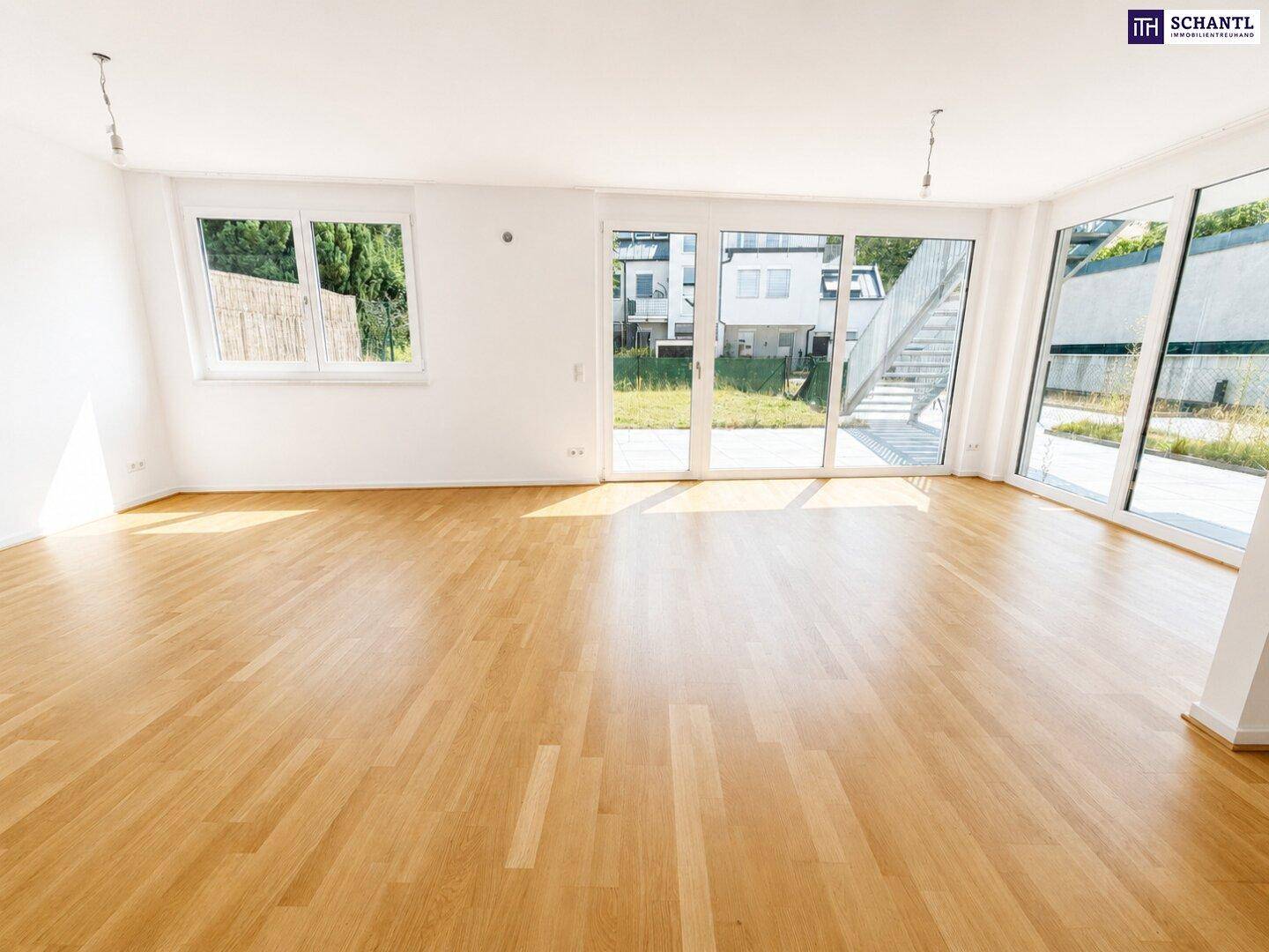 Helles Wohnzimmer mit großen Fensterfronten, Holzboden und Zugang zur Terrasse.