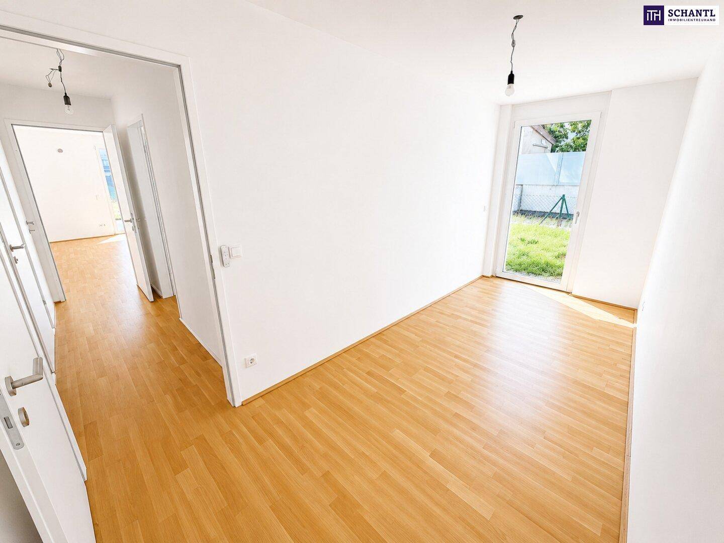 Geräumiges Schlafzimmer mit Holzboden und Zugang zu einem hellen Flur.