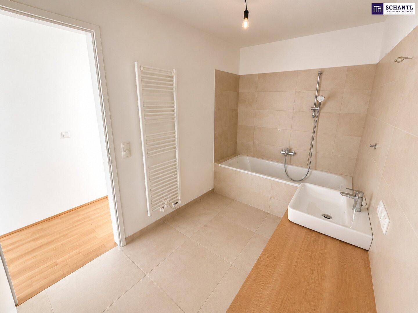 Modernes Badezimmer mit Badewanne, Waschbecken und beheiztem Handtuchhalter.
