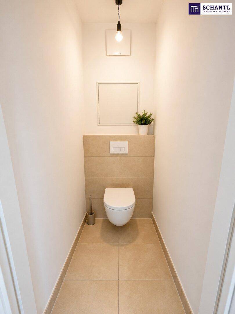 Separates Gäste-WC mit Wand-WC und modernen Fliesen an den Wänden.