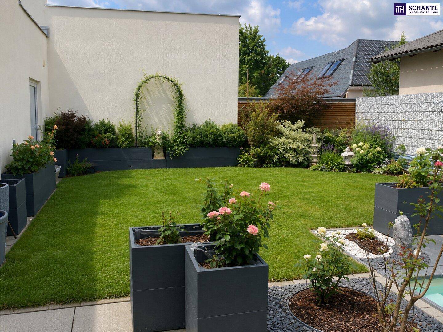 Gepflegter Garten mit Rasenfläche, Blumenbeeten und dekorativen Pflanzkübeln an der Hauswand.