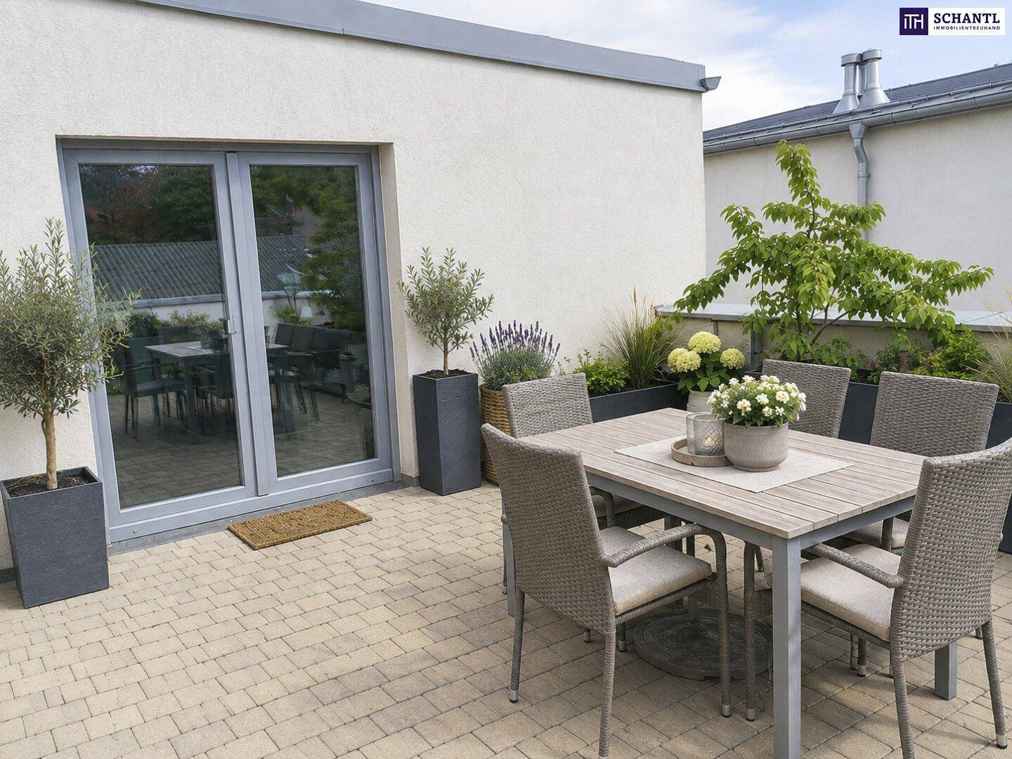 Möblierte Dachterrasse mit Esstisch, Stühlen und dekorativen Pflanzen in Kübeln.