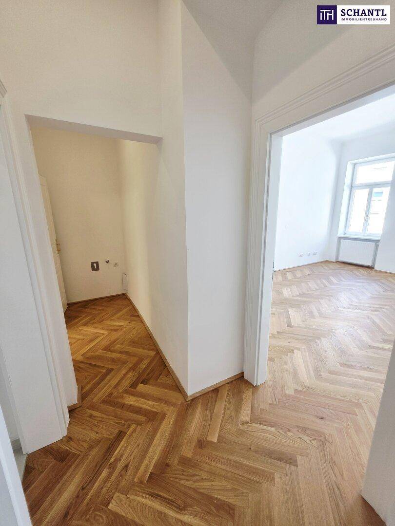 Flur mit Fischgrätparkett und Zugang zu weiteren Räumen, inklusive einem Bereich für Anschlüsse.