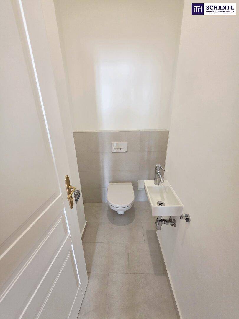Modernes Gäste-WC mit wandhängender Toilette und kleinem Handwaschbecken, hell gefliest.