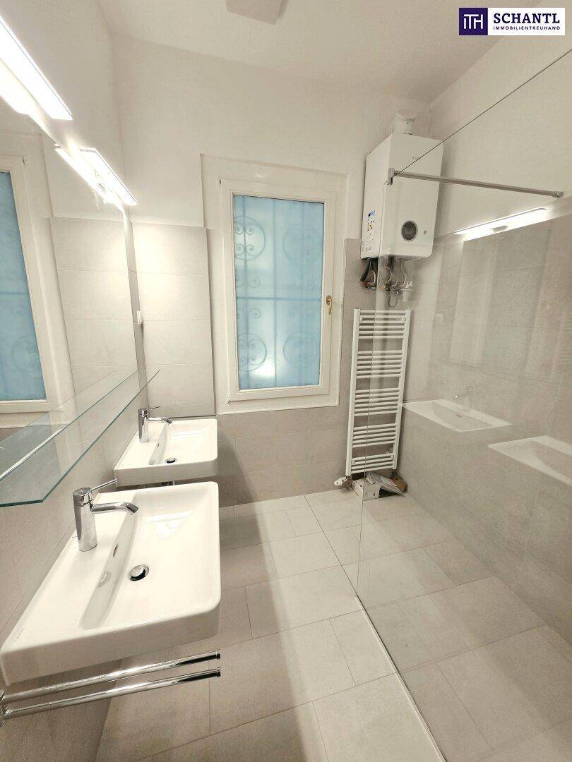 Modernes Badezimmer mit zwei Waschbecken, großer Dusche und Fenster für natürliche Belüftung.