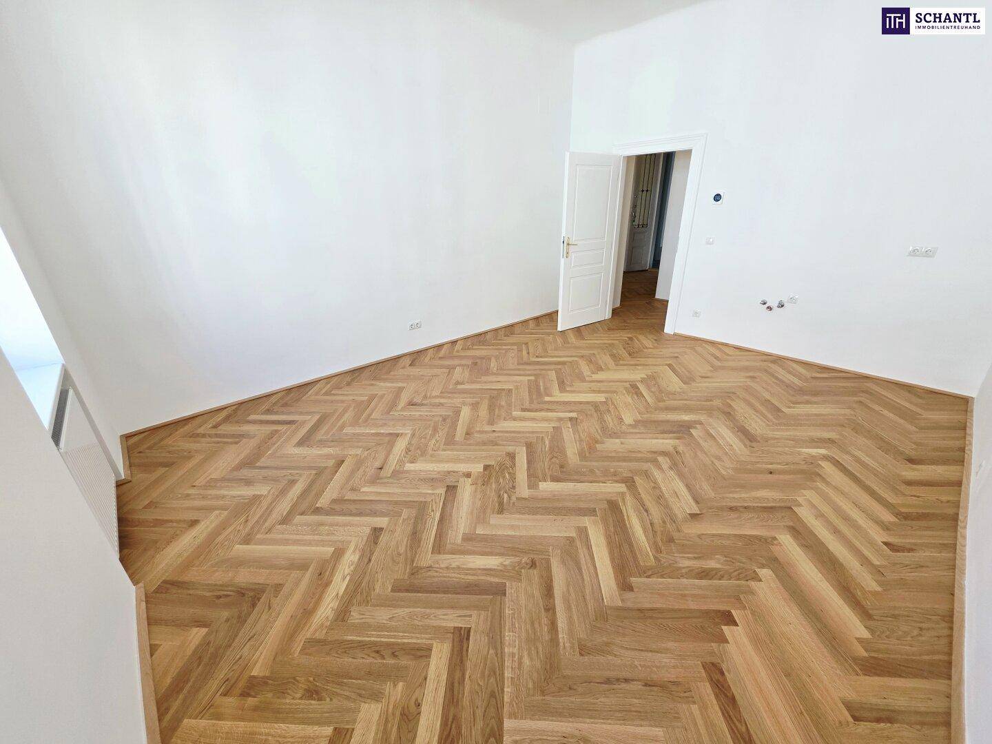 Heller Raum mit elegantem Fischgrätparkett und weiß gestrichenen Wänden, bereit zum Einzug.