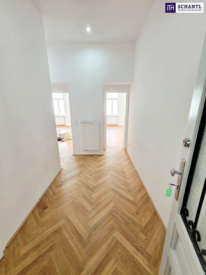 Heller Flur mit Fischgrätparkett, der zu weiteren Zimmern führt, frisch renoviert.