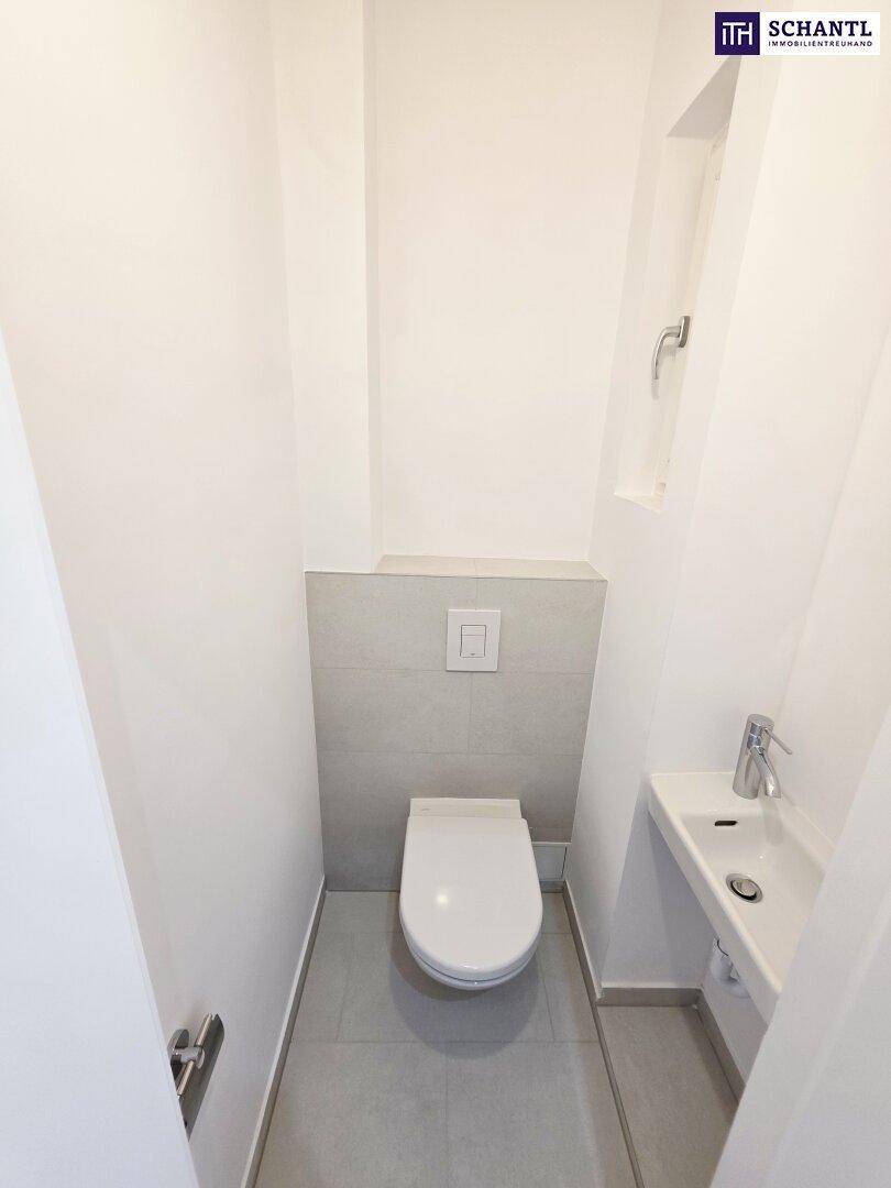 Modernes Gäste-WC mit wandhängendem WC und kleinem Waschbecken, hell gefliest.