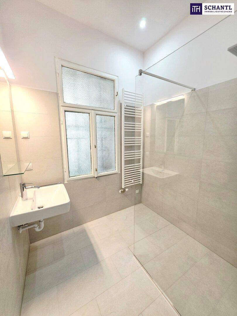 Helles Badezimmer mit moderner Dusche, Waschbecken und beheiztem Handtuchhalter.