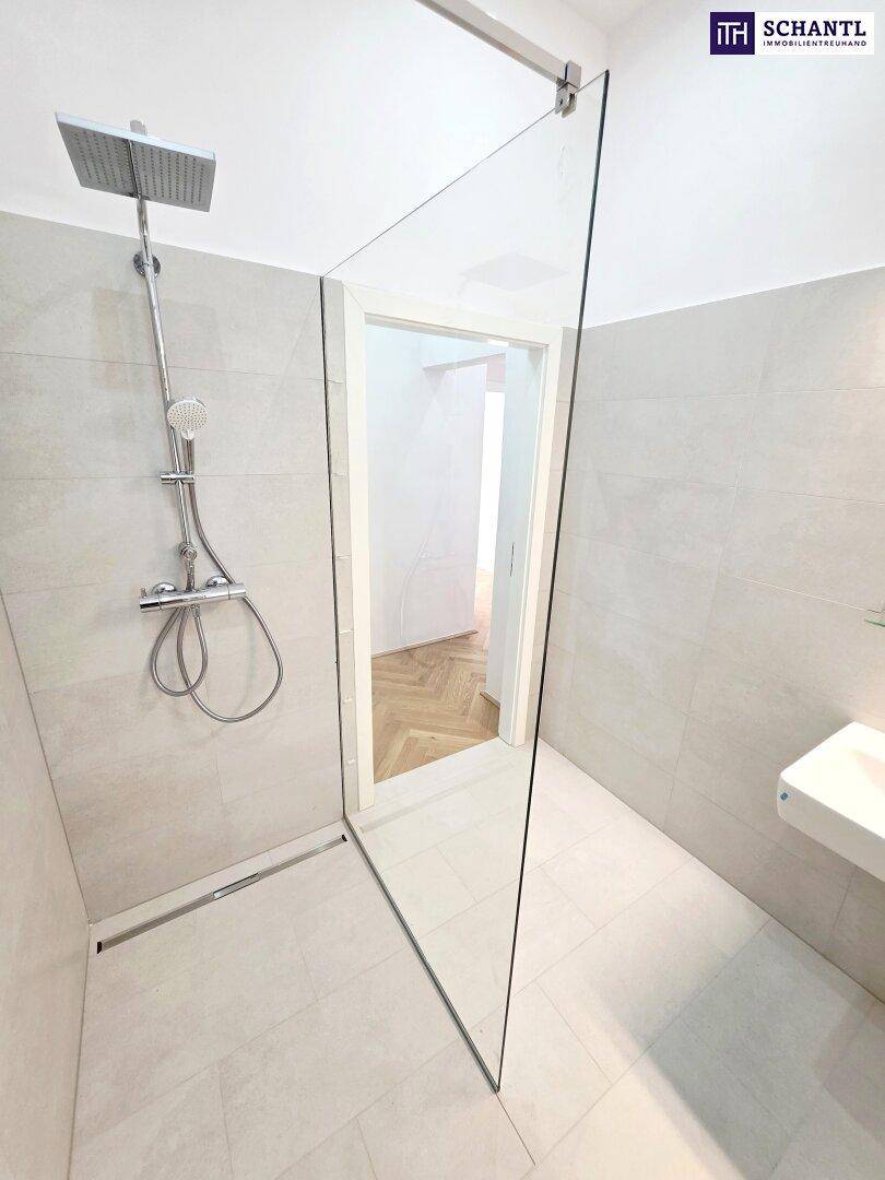 Moderne Dusche mit Glasabtrennung, Regenduschkopf und hellen Fliesen im Badezimmer.