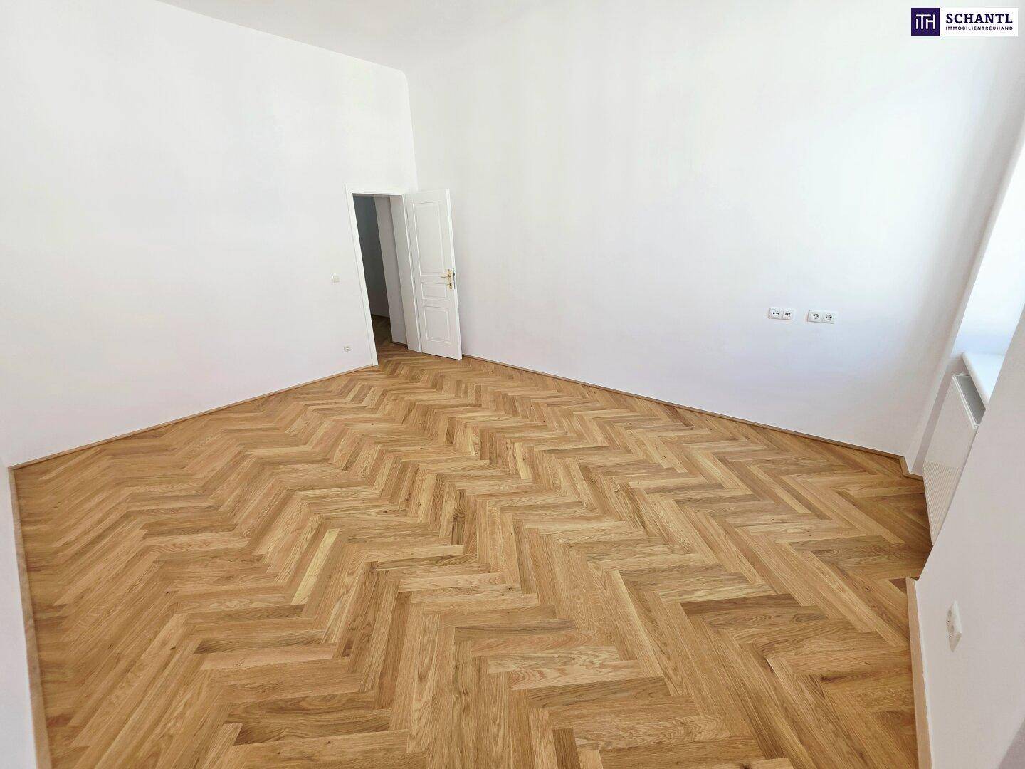 Geräumiges Zimmer mit Fischgrätparkett und weiß gestrichenen Wänden, bereit zur Nutzung.