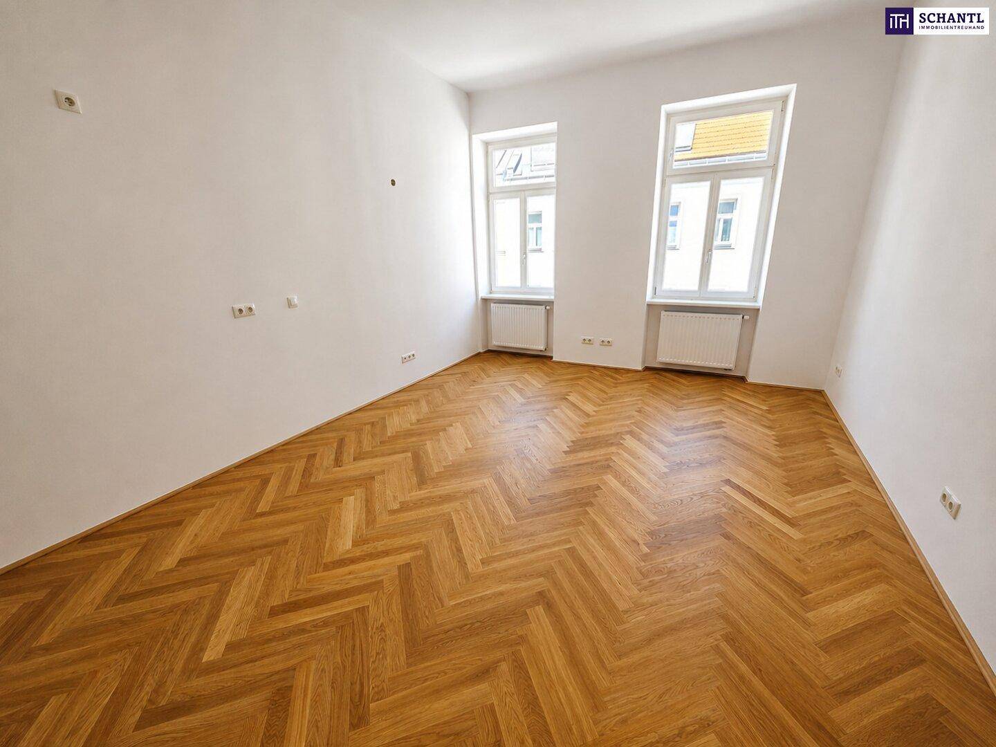 Geräumiges Zimmer mit neu verlegtem Fischgrätparkett und viel Tageslicht durch zwei Fenster.