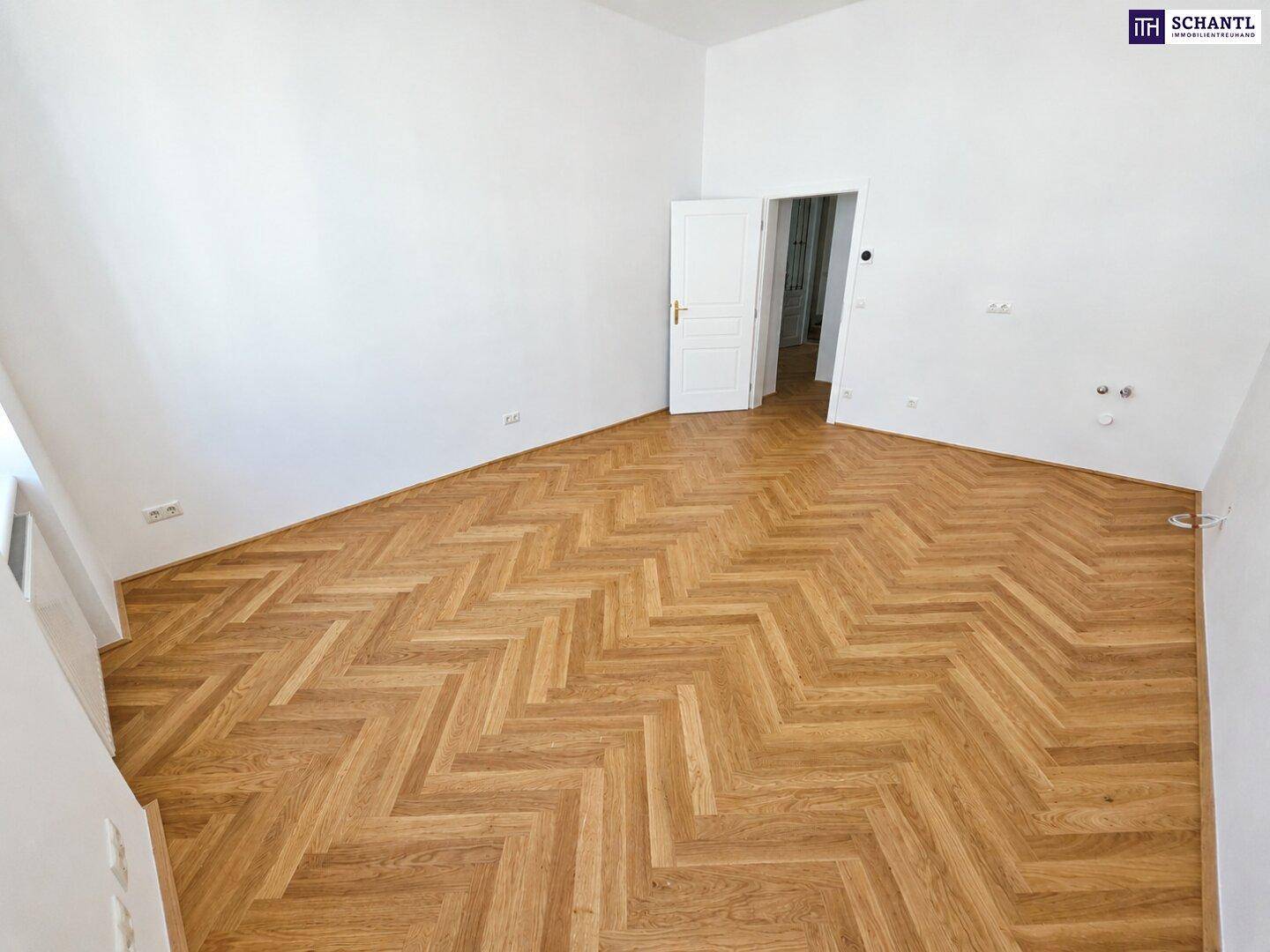 Heller Raum mit Fischgrätparkett und Zugang zu einem weiteren Zimmer, frisch renoviert.