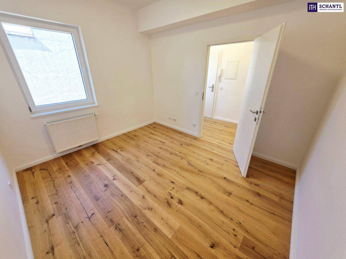 Helles Schlafzimmer mit Holzboden und Dachfenster, das viel natürliches Licht hereinlässt.