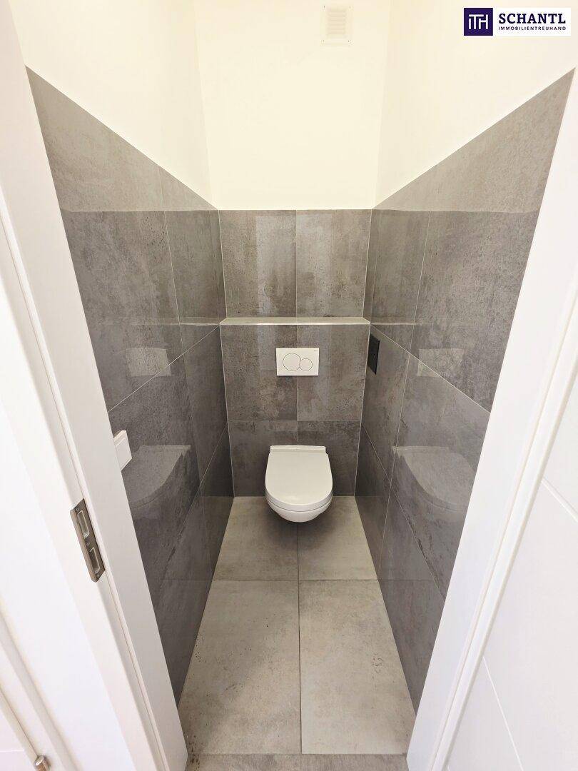 Modernes Gäste-WC mit grauen Fliesen und wandhängendem WC, minimalistisch gestaltet.
