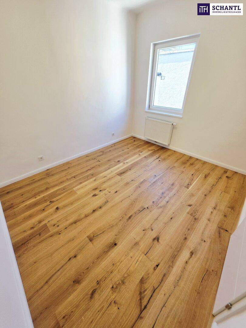 Freundliches Zimmer mit Holzboden und schrägem Fenster, das eine angenehme Atmosphäre schafft.