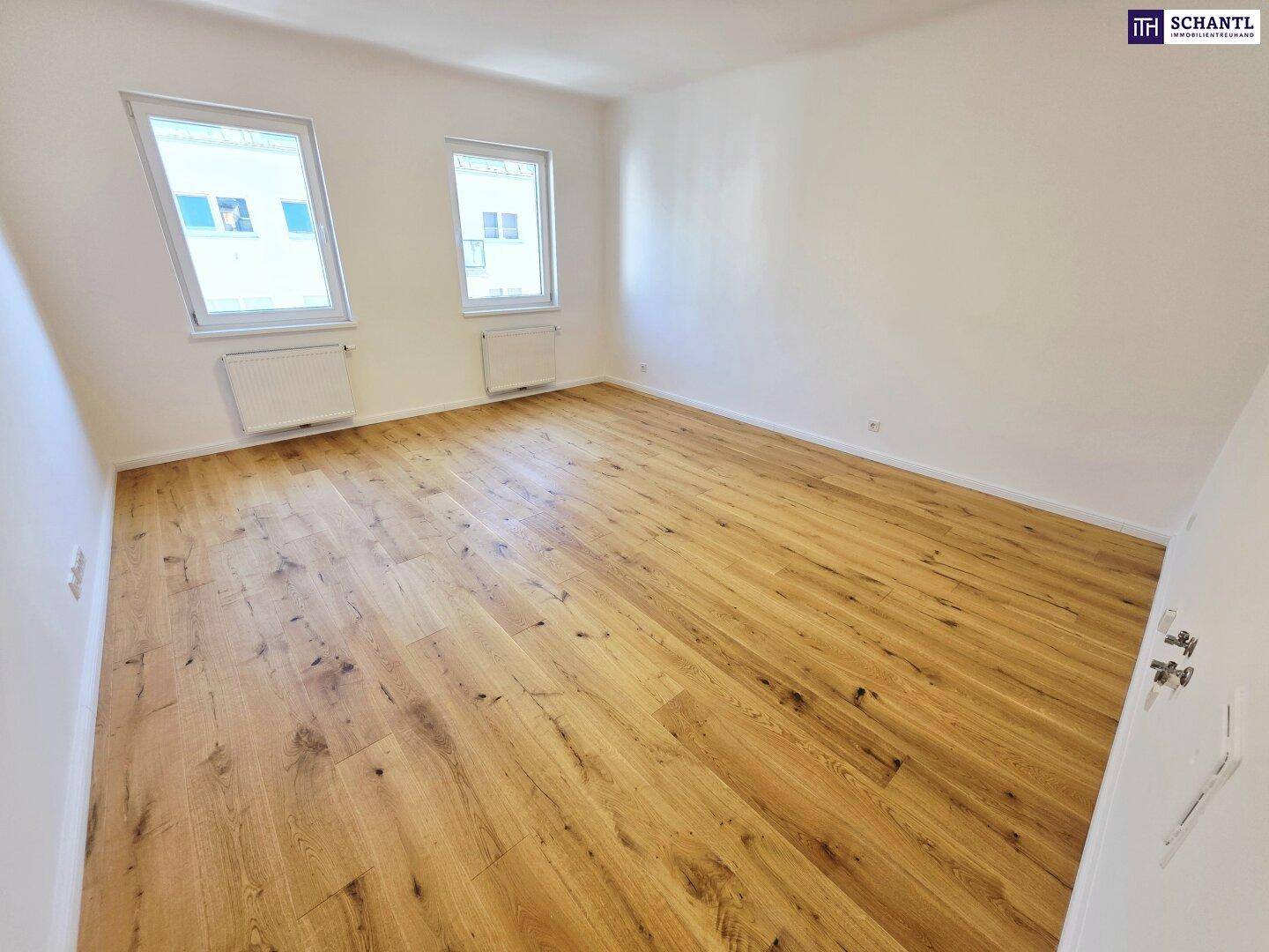 Helles Zimmer mit Holzboden und zwei Dachfenstern, die für viel Lichteinfall sorgen.