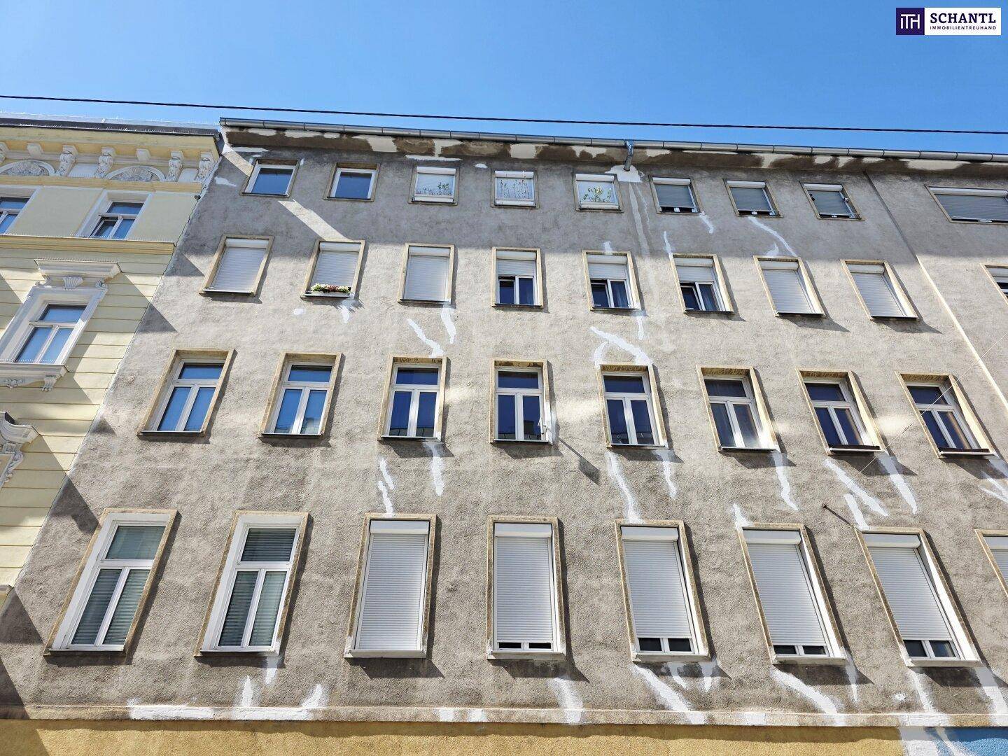 Fassade eines Altbaus mit zahlreichen Fenstern, einige davon mit Rollläden ausgestattet.