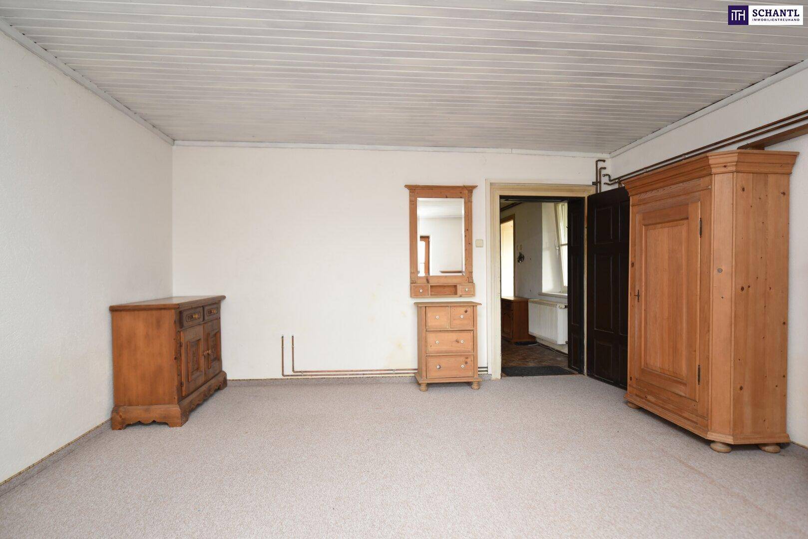 Schlafzimmer mit Teppichboden, traditionellen Holzmöbeln und einem Spiegel, der den Raum erweitert.