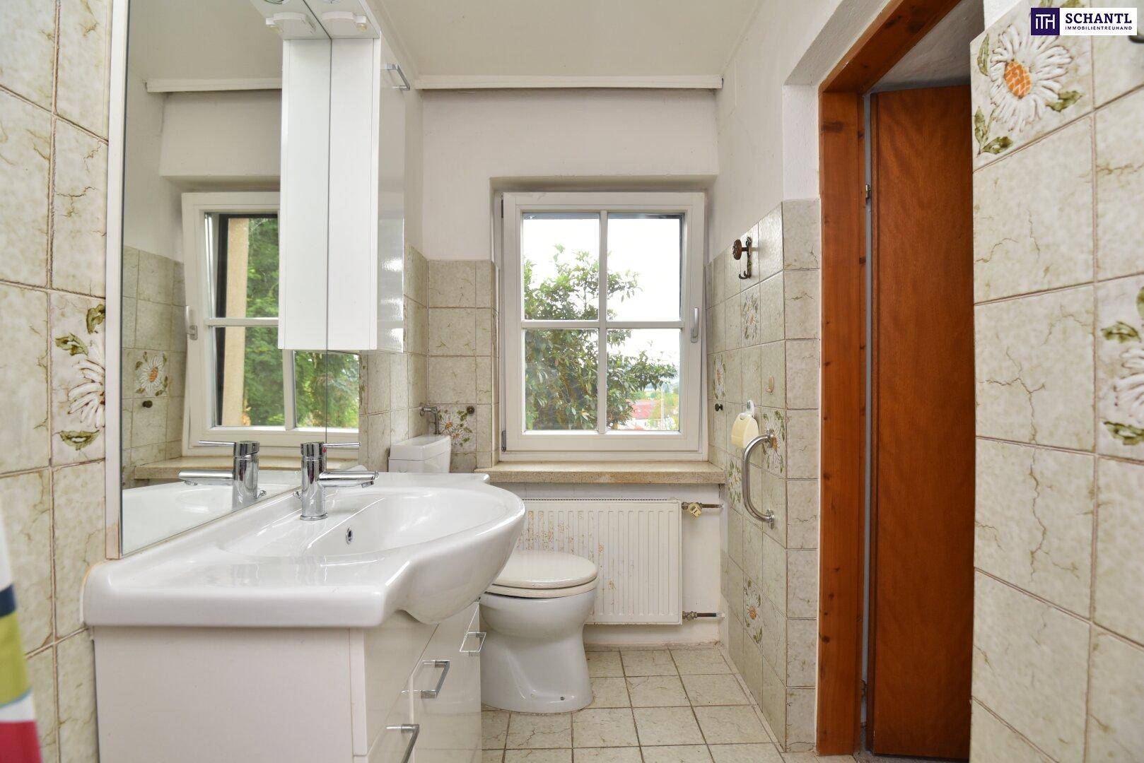 Helles Badezimmer mit WC, Waschbecken und Fenster, das Tageslicht hereinlässt.