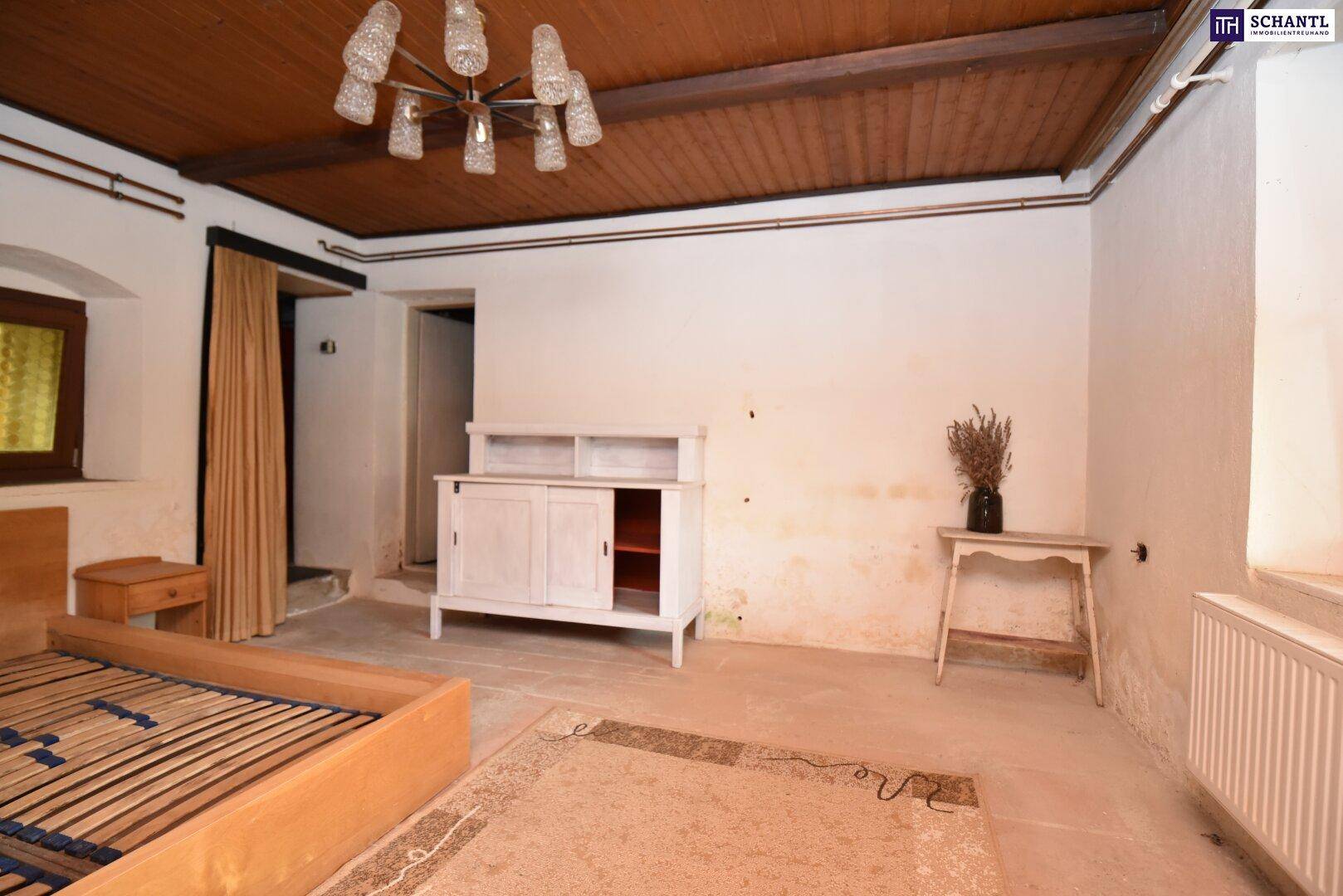 Geräumiges Schlafzimmer mit Holzbalkendecke, Holzbett und einem weißen Schrank.