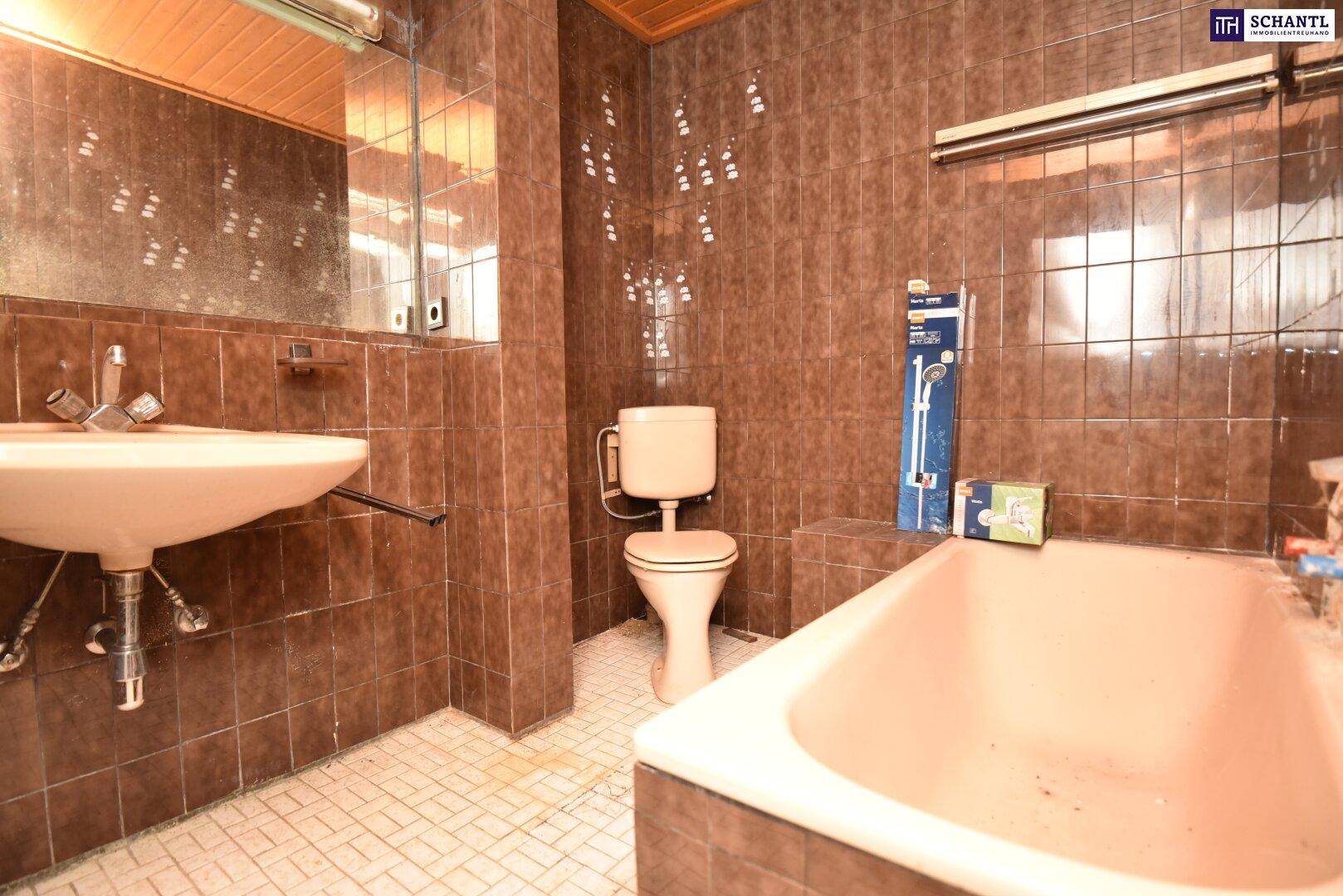 Badezimmer mit braunen Fliesen, Waschbecken, Toilette und einer Badewanne.