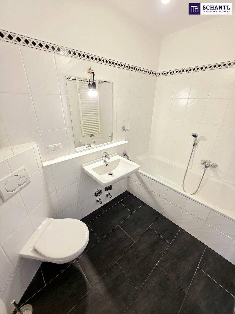 Modernes Badezimmer mit Badewanne, WC, Waschbecken und dunklen Bodenfliesen.