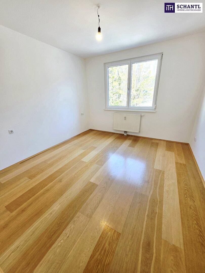 Helles Schlafzimmer mit Holzboden und Fensterblick ins Grüne, bietet eine ruhige Atmosphäre.