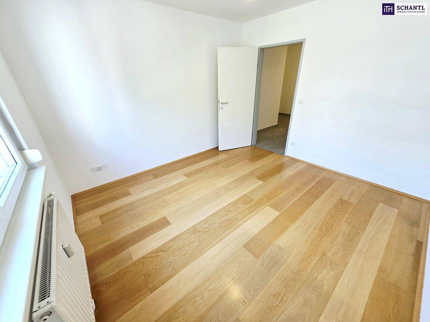 Helles Schlafzimmer mit Holzboden und weiß gestrichenen Wänden, bereit zur individuellen Gestaltung.