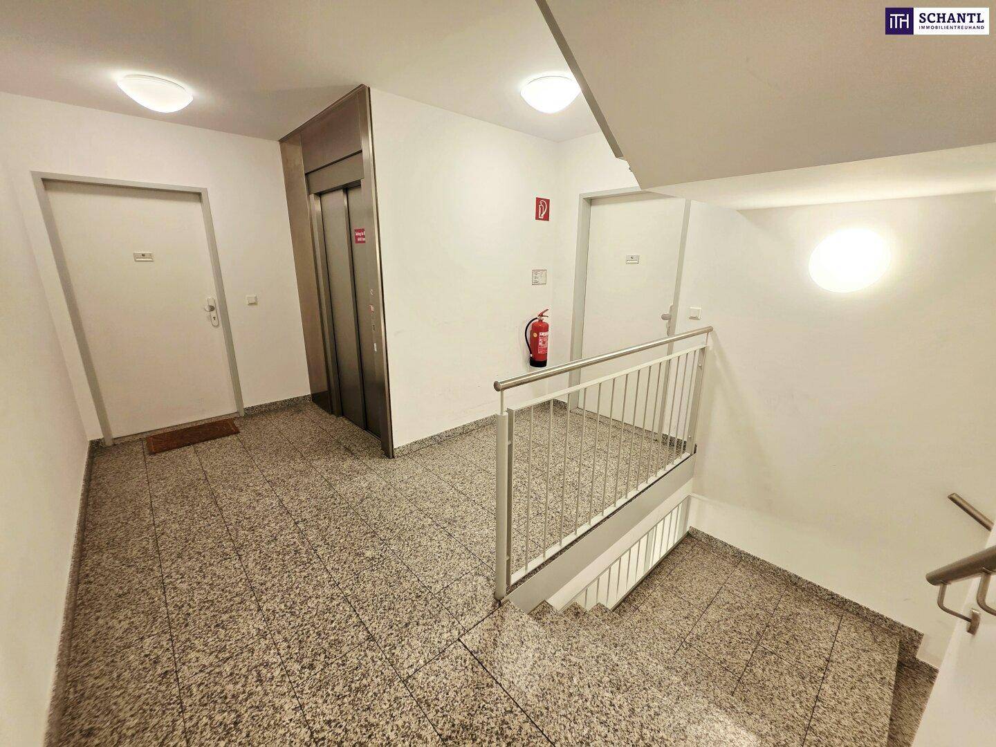 Heller Treppenhausbereich mit Aufzug und Granitfliesenboden im Mehrfamilienhaus.