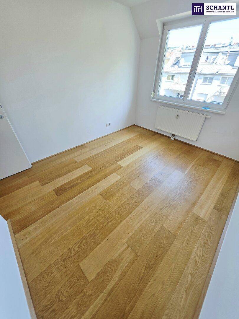 Freundliches Zimmer mit Holzparkett und großem Fenster, das viel Tageslicht hereinlässt.
