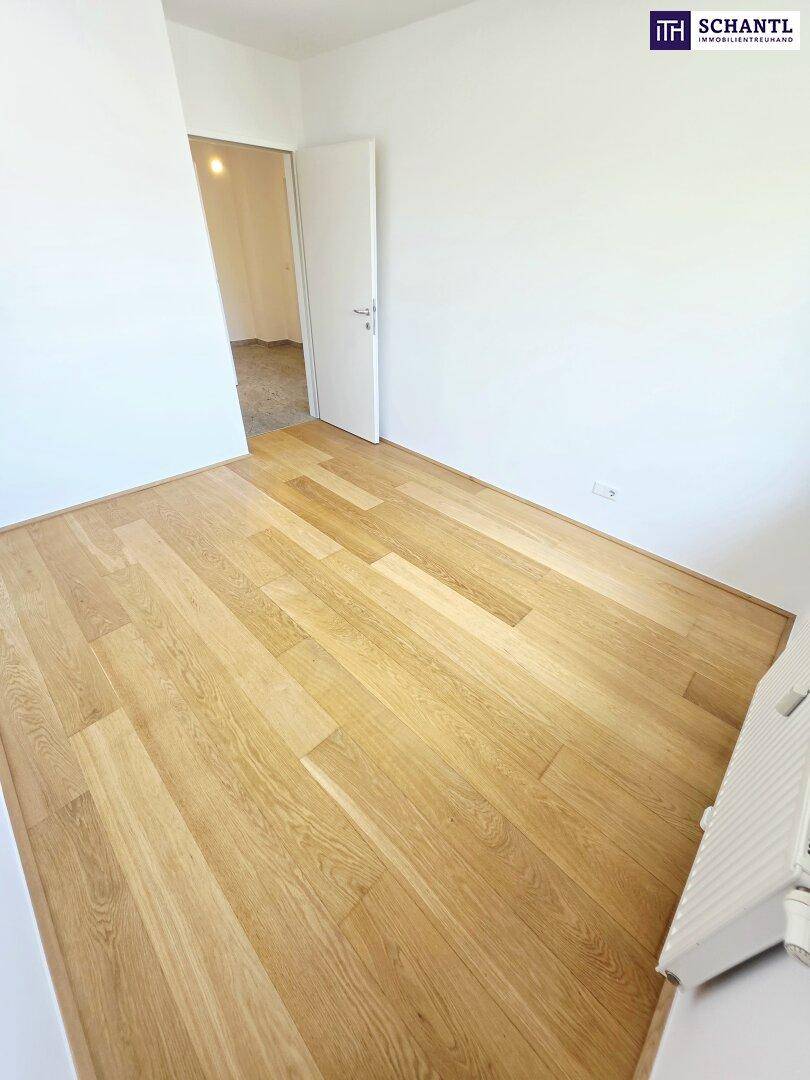 Geräumiges Zimmer mit Holzparkettboden und weiß gestrichenen Wänden, ideal für ein Schlafzimmer.
