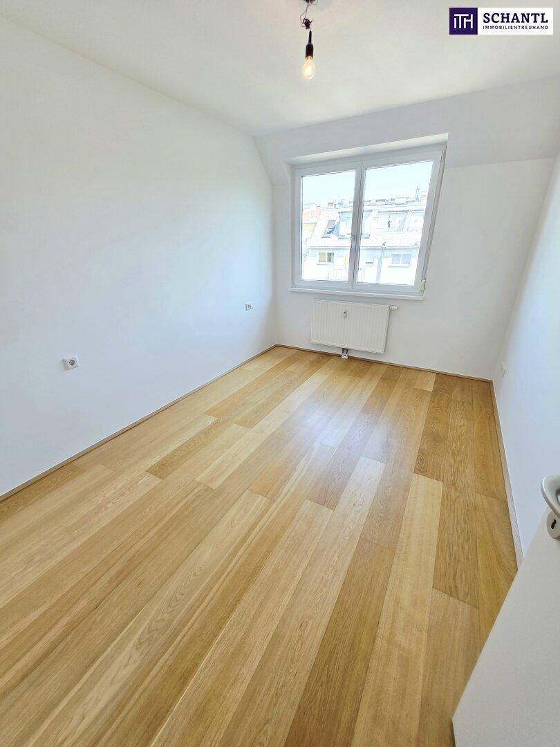 Helles Schlafzimmer mit Holzparkettboden und großem Fenster mit Stadtblick.