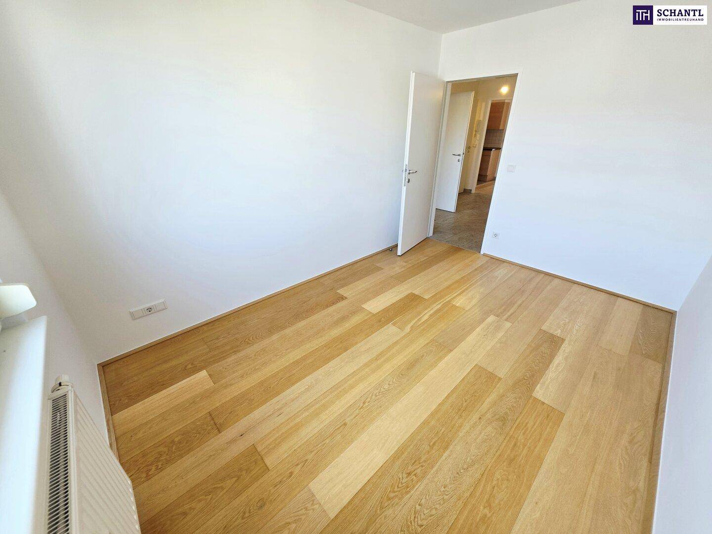 Leeres Zimmer mit Holzparkettboden und weiß gestrichenen Wänden, bereit zum Einzug.