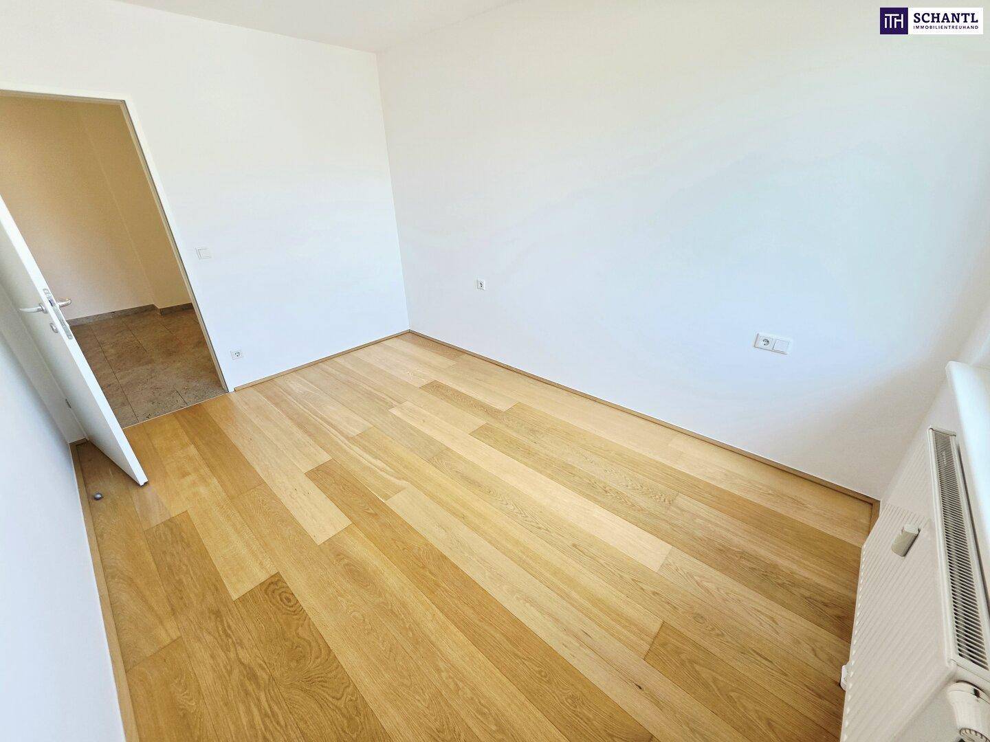 Helles, leeres Zimmer mit neuem Holzparkettboden und weißen Wänden, bereit zum Einzug.