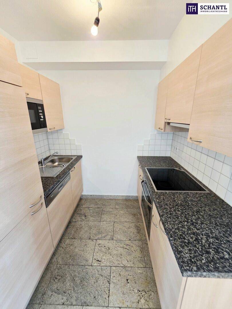Funktionale Küche mit hellen Holzschränken, Granitarbeitsplatten und integrierten Geräten.