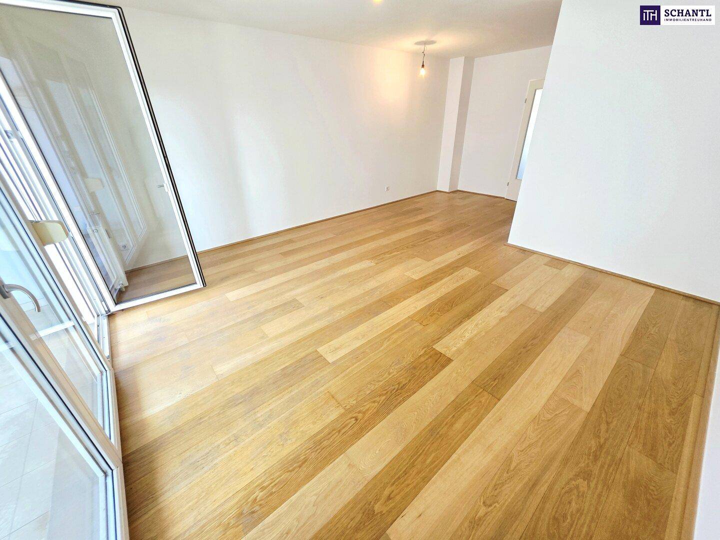 Geräumiger, heller Wohnbereich mit hochwertigem Holzparkett und weiß gestrichenen Wänden.