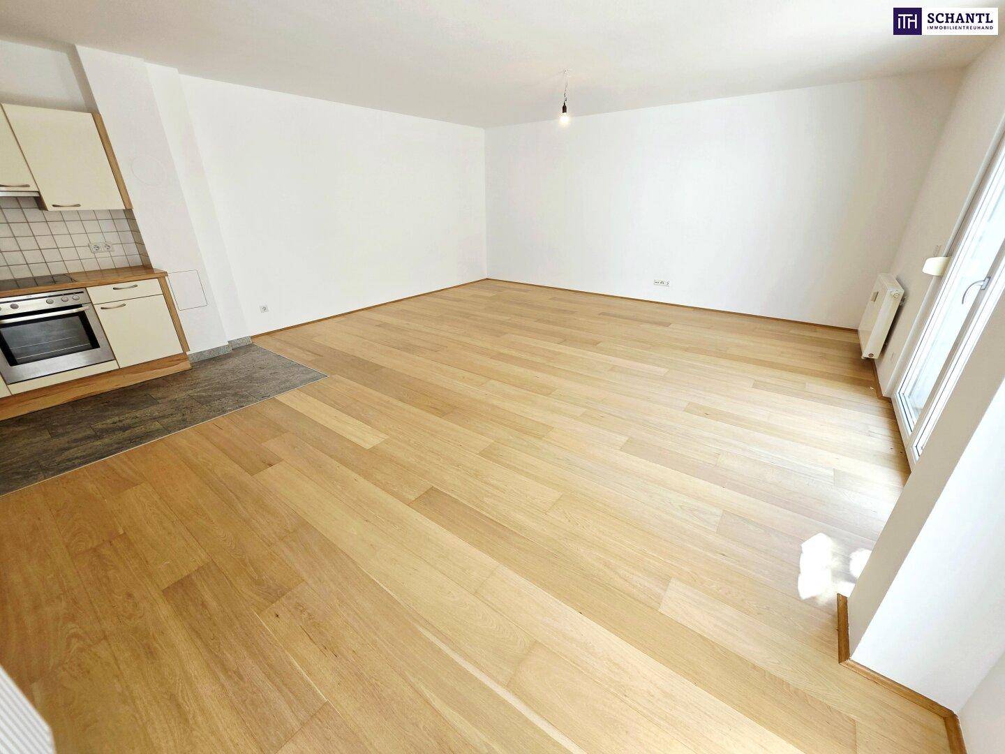 Offener Wohnbereich mit Holzboden und integrierter Küchenzeile, bereit zur individuellen Gestaltung.
