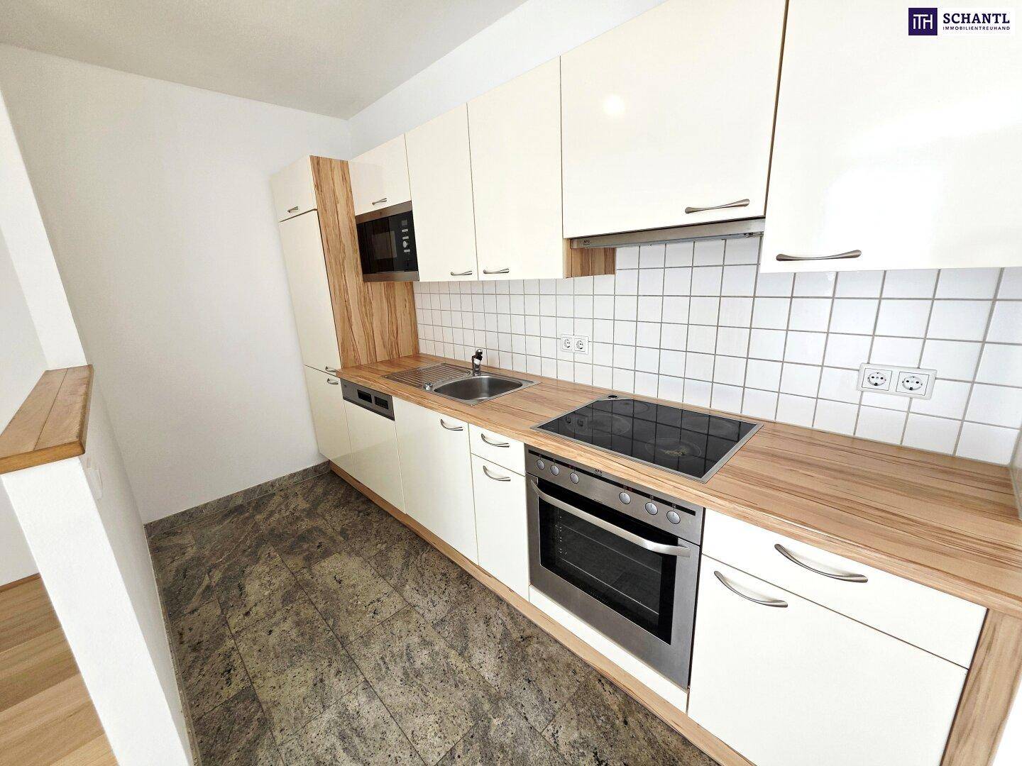 Moderne Einbauküche mit weißen Hochglanzfronten, Holz-Arbeitsplatte und integrierten Geräten.