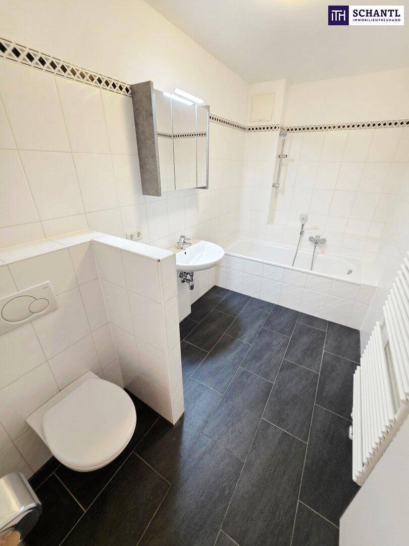 Helles Badezimmer mit Badewanne, WC und Waschbecken, ausgestattet mit modernen Fliesen.