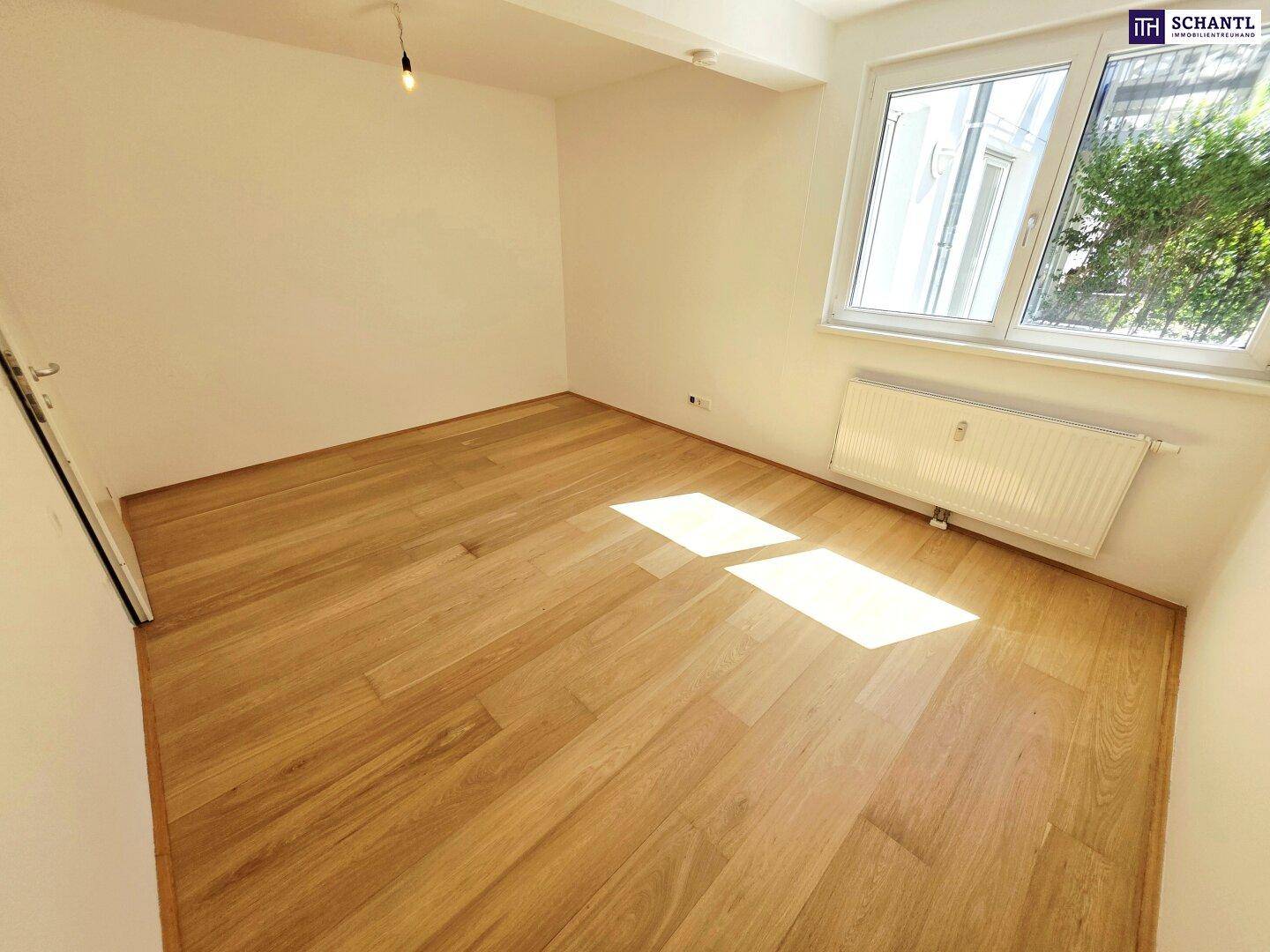 Helles Schlafzimmer mit Holzboden und Fenster, das viel Tageslicht hereinlässt.