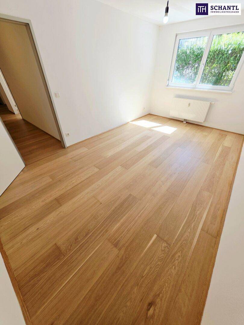 Freundliches Schlafzimmer mit Holzboden und Blick ins Grüne, bietet eine angenehme Atmosphäre.