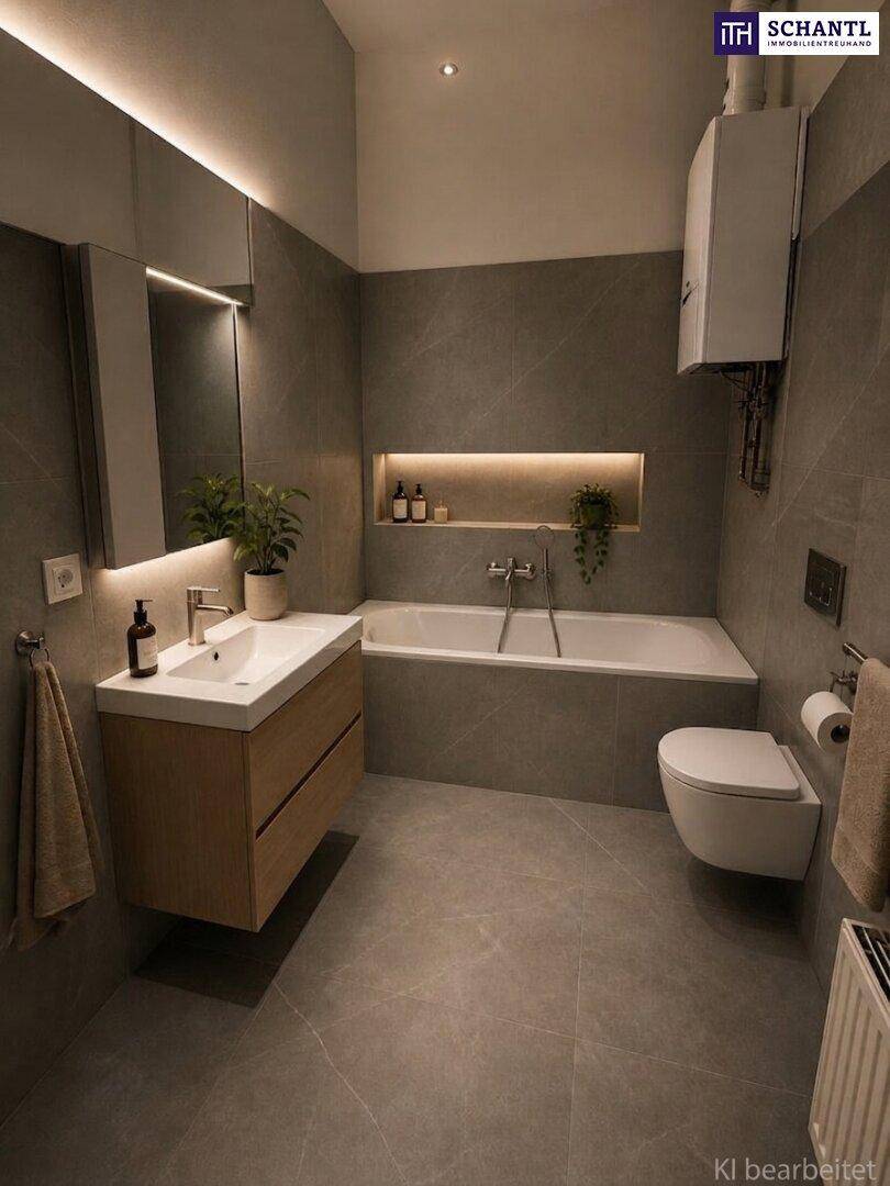 Modernes Badezimmer mit grauen Fliesen, integrierter Badewanne und schwebendem Waschtisch mit beleuchtetem Spiegelschrank.