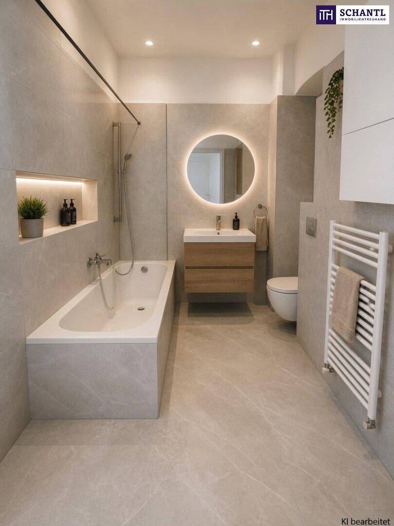 Modernes Badezimmer mit hellgrauen Fliesen, Badewanne, beleuchtetem Spiegel und beheiztem Handtuchhalter.