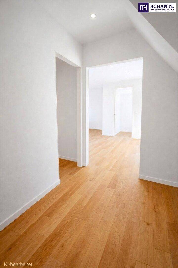 Heller Flur mit Holzboden und weißen Wänden, der zu weiteren Räumen führt.