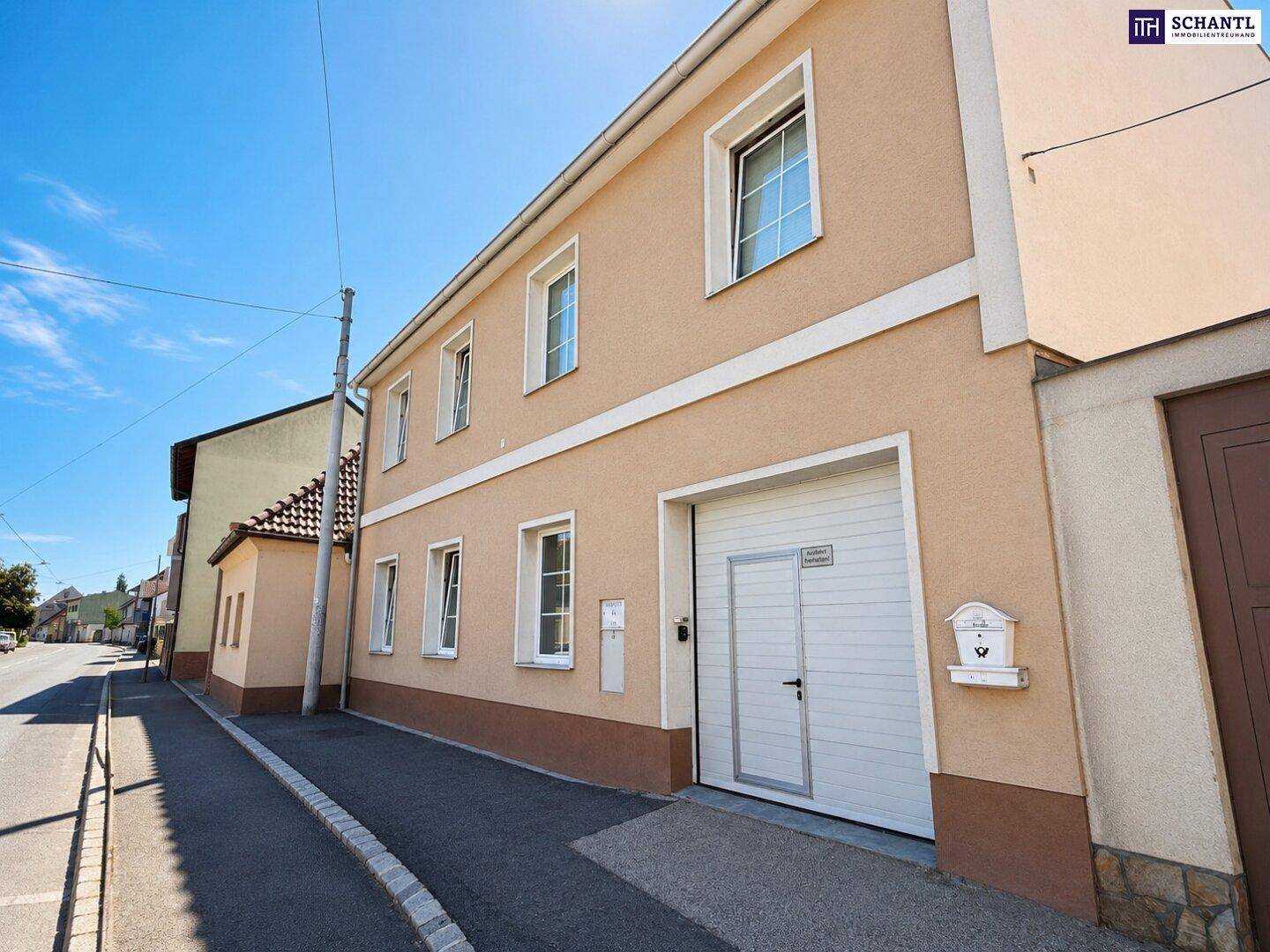 Ansicht der Hausfassade von der Straße mit Garage und mehreren Fenstern.