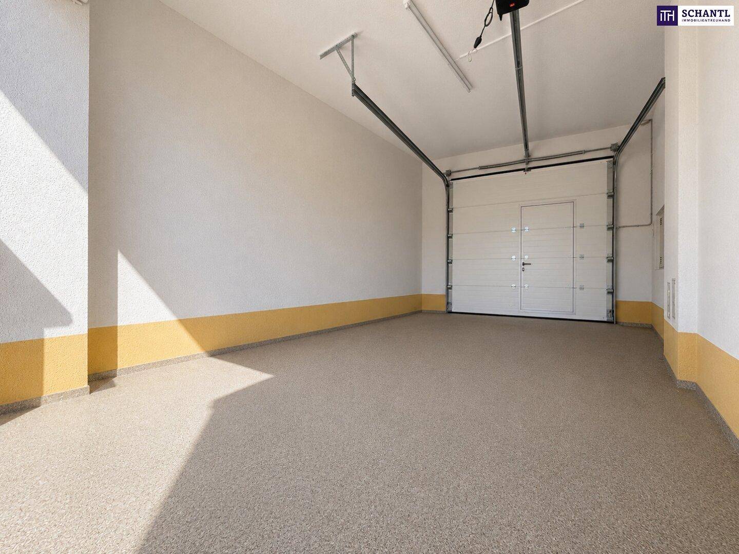 Geräumige Garage mit automatischem Tor und robustem Bodenbelag, bereit zur Nutzung.