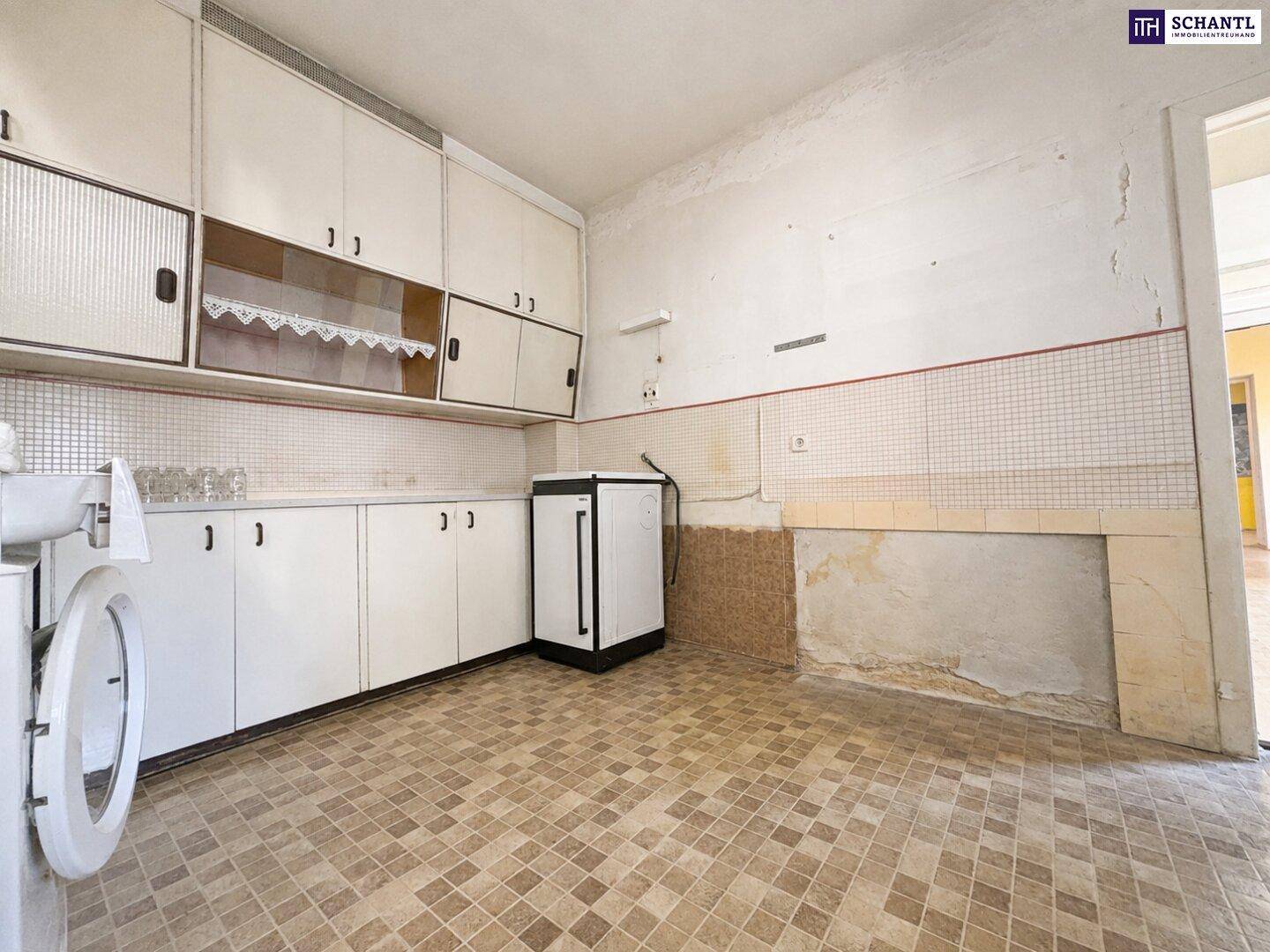 Küche in Originalzustand mit älteren Einbauschränken und gefliestem Boden, bereit zur Modernisierung.